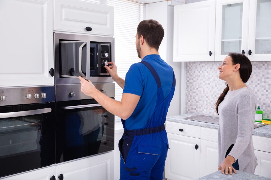 Technician repairing microwave oven at home for kitchen appliance maintenance